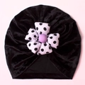 Detail of baby velvet turban hat featuring a large black and white polka dot flower - Black