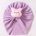 Close-up of lilac waffle knit baby turban hat with a cute pink plush piglet decoration - Purple