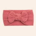 Detailed close-up of a pink baby headband featuring a waffle texture and large soft bow - Dark Mauve
