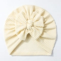 Detailaufnahme der hellgelb gestreiften Babymütze mit einer großen Zierschleife - Beige