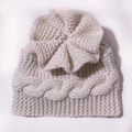 Detalle de gorro de punto trenzado para bebé con gran flor artesanal y borde acanalado - Beige