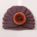 Detail van donkerpaarse geribbelde baby muts met oranje fluwelen pompoen decoratie - Taropaars