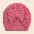 Detail der Baby Turban Mütze aus rosa Waffelstrick mit einer großen Schleife dekoriert - Dunkelmalve