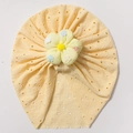 Detail of baby turban hat featuring a pale yellow hollow knit and a large floral accent - Yellow