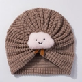 Close-up of baby turban hat featuring brown corn kernel fabric and cute white cloud decor - Coffee