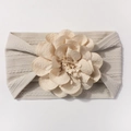 Détail du bandeau bébé en nylon beige avec texture torsadée et grande fleur en tissu doux - Gris