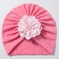 Détail de texture en tricot doux et fleur en tissu sur un bonnet pour bébé rose vif - Rose