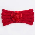 Detailed macro view of a red knitted baby headband featuring a large satin flower ornament - Red