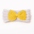 Detail shot of newborn knit headband with yellow bow on soft beige wool background - Beige + Yellow
