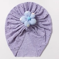Detail der lila Baby-Turbanmütze mit Lochmuster und einer großen blauen Stoffblume - Lila