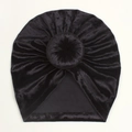 Detail of black velvet baby turban hat featuring pleated texture and bun decoration - Black