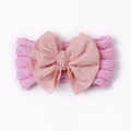 Detail eines rosa gestrickten Babystirnbaends mit großer Schleife und Rippstruktur - Nute Rosa