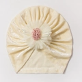 Détail du bonnet de bébé en velours crème avec une grande fleur en dentelle blanche - Beige