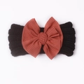 Close-up of black knitted baby headband with a large rust red ribbed textured bow - Black