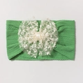 Détail d'un bandeau bébé en tricot vert avec un grand nœud en dentelle blanche - Vert