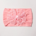 Detailed macro view of pink ribbed baby headband with a large lace bow decoration - Pink