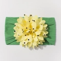 Detail of green knit baby headband featuring a yellow polka dot flower on white background - Green