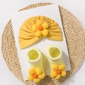 Detailed macro view of yellow knitted baby turban hat and matching socks with sunflower - Yellow