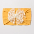 Détail d'un bandeau bébé en tricot jaune gingembre avec un gros nœud en dentelle blanche - Jaune