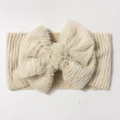 Détail d'un bandeau pour bébé en peluche crème avec un grand nœud en fausse fourrure - Beige