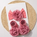 Close-up of pink baby headband and floral socks set on a natural woven mat - Dark Mauve