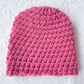 Detailed macro view of pink chunky knit baby beanie showing warm yarn texture and stitching - Dark Mauve
