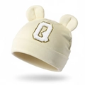 Close-up of baby beanie with plush ears and golden glitter letter Q patch on soft knit - Beige
