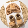 Close-up of khaki infant knit hat and socks set featuring 3D plush teddy bear ornaments - Coffee