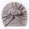 Macro detail of oatmeal knitted baby turban hat with a cute plush puppy decoration - Gray