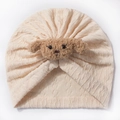 Dettaglio del turbante neonato in maglia a trecce color crema con un tenero orsetto - Beige