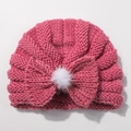 Detail of rose pink cable knit baby hat featuring large bow and fluffy white pom-pom decoration - Dusky Pink