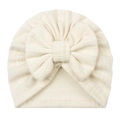 Detail of baby turban hat showing cream white jacquard knit texture and large bow - Beige