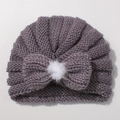 Detail of knitted baby turban hat with bow and white faux fur pompom in dusty pink - Gray