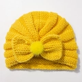 Close-up of mustard yellow knit baby turban with a large bow and soft faux fur pom-pom - Yellow