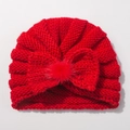 Detail of red knit baby turban hat with a large bow and soft faux fur pom-pom - Red