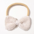 Detail von cremefarbenem Strickbogen auf elastischem Nylon-Babystirnband mit Webstruktur - Beige