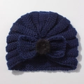 Close-up of navy blue knit baby hat with bow design and black pom-pom detail - Navy Blue