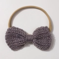 Macro detail of hand-knitted purple bow on soft elastic headband for infants - Gray