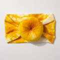 Detailed texture of yellow and white tie-dye elastic baby headband with central knot - Khaki/Earth Yellow