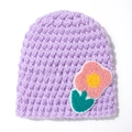 Detailed close-up of a purple knitted baby hat with a vibrant floral embroidered patch - Purple