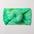 Detail of green tie-dye elastic baby headband with soft pleated donut design on white base - Green