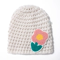 Detailed view of handmade cream crochet knit baby hat with pink flower embroidery patch - Beige