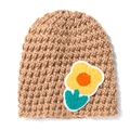 Detailed knit texture of light brown baby hat featuring yellow crochet flower ornament - Coffee