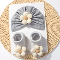 Dettaglio del set cappello e calze in maglia grigia per neonati con fiori 3D su fondo intrecciato - Grigio