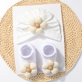 Dettaglio del set cappello e calzini per neonato in maglia bianca con fiori decorativi - Bianco