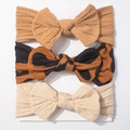 Detail van een baby hoofdbandenset met gebreide texturen en luipaardstrikken op witte kaart - Beige Koffie Bruin C