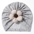 Close-up of grey knit baby beanie featuring a beige corduroy flower and braided texture - Gray