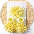 Detail von gelbem Baby-Stirnband und Socken Set mit großen Blumen auf gewebter Matte - Beige