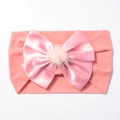 Détail d'un bandeau en nylon pour bébé avec gros nœud en satin et pompon rose sur blanc - Vieux rose