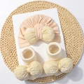 Set cappello e calzini neonato rosa con fiocchi floreali su tappetino di paglia - Set Berretto e Calzini / Rosa Carne